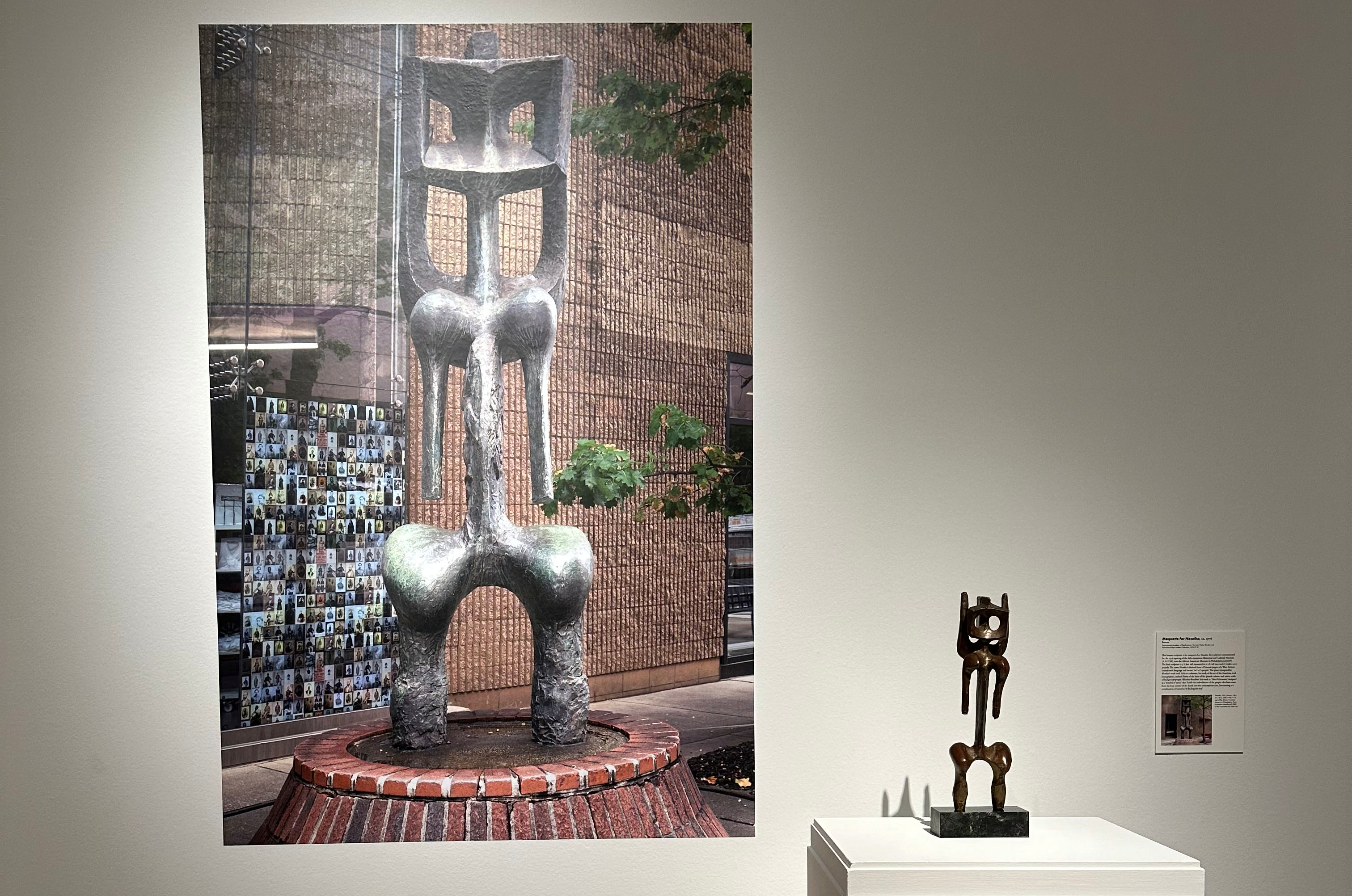 Installation view of Nesaika maquette with an image of the full sculpture in the background.