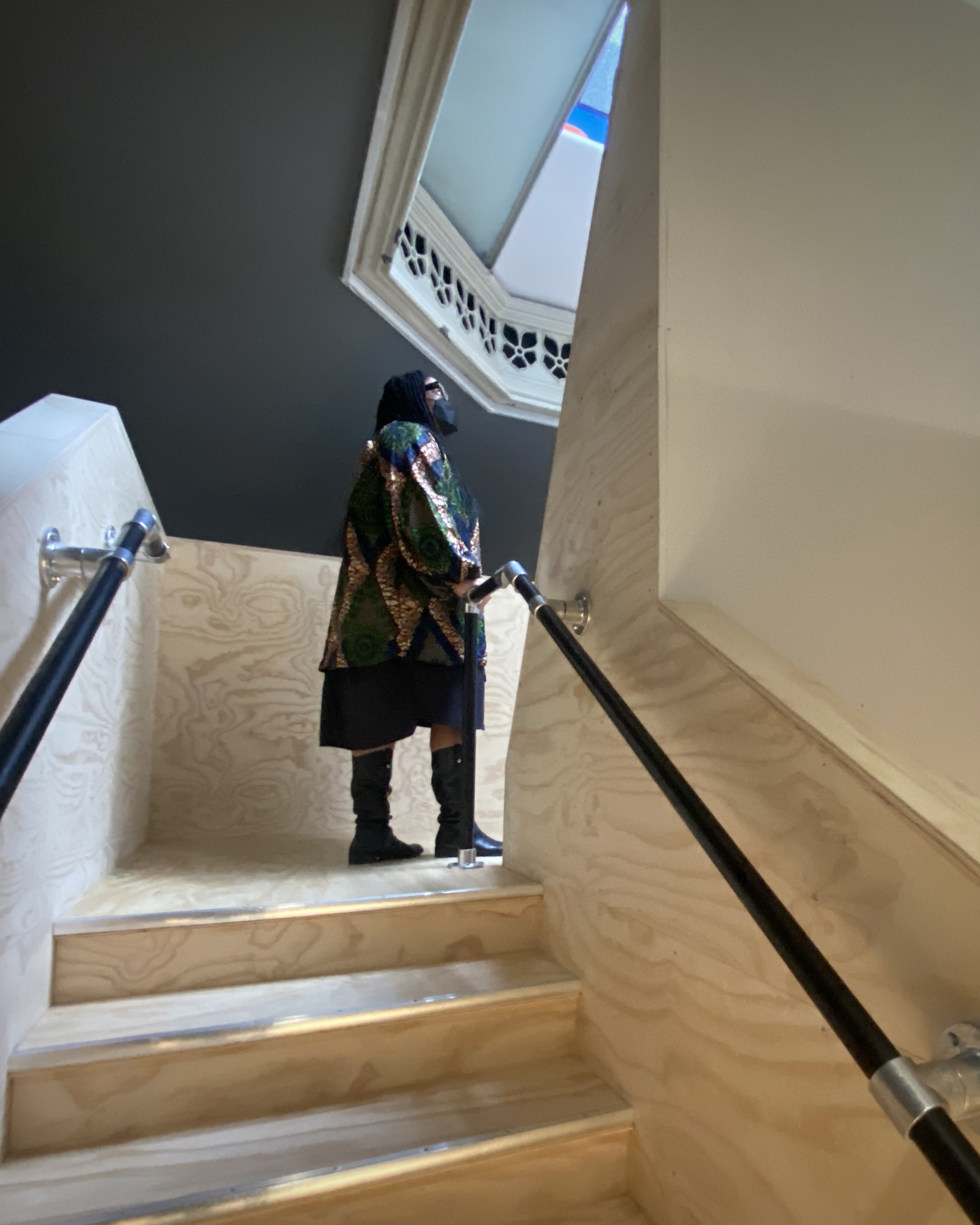 person on staircase landing looking up toward skylight