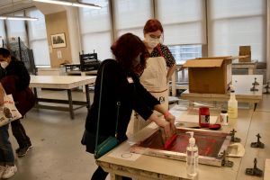 A student screen printing their own PAFA tote bag