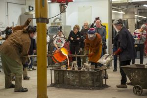 A group of people watching a bronze pour