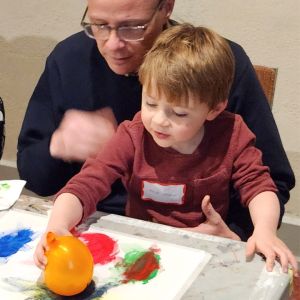 A man and a young boy engaging in a common children's art activity: balloon painting. 