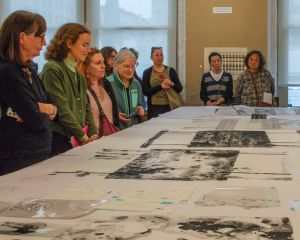 people gathered around a table looking at prints