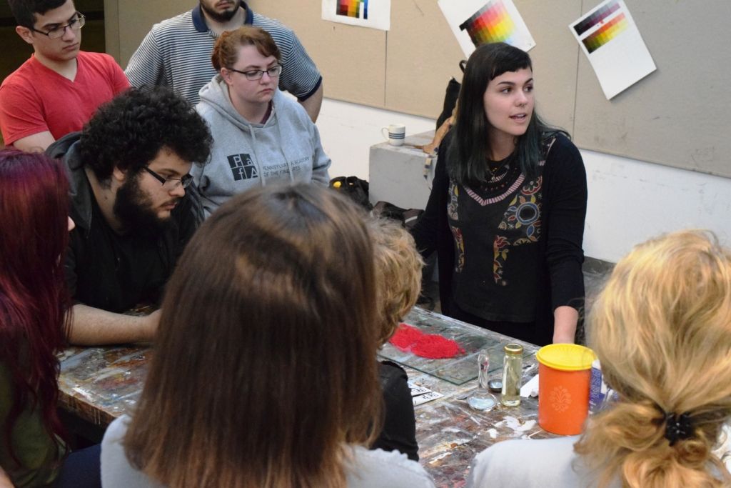 Students surround a table where Liza Samuel is standing