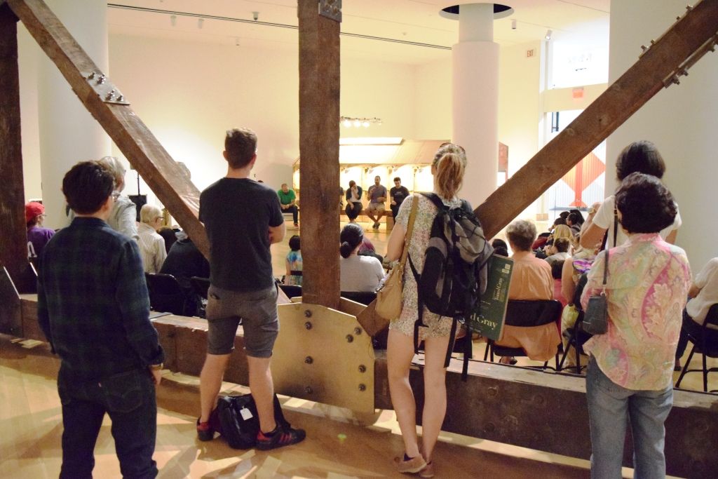 Five people standing behind a group of people on the floor watching the assembly