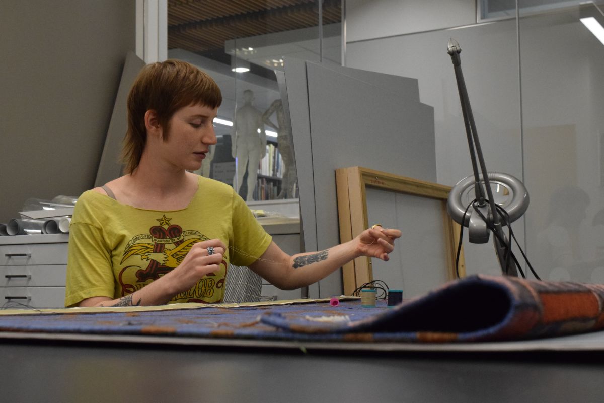 Artist Jessica Willittes sews in the conservation office