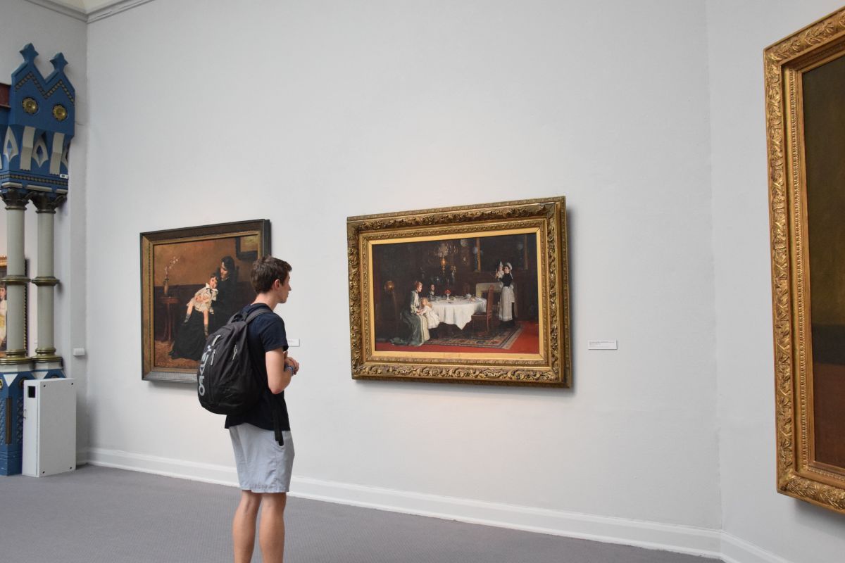 A student looks at a painting in the museum