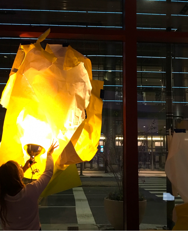 A person holding up a lamp under an artwork