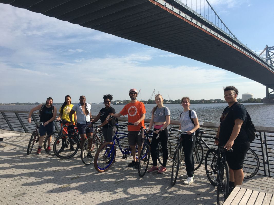 group of students on bike ride in front of river in Philly