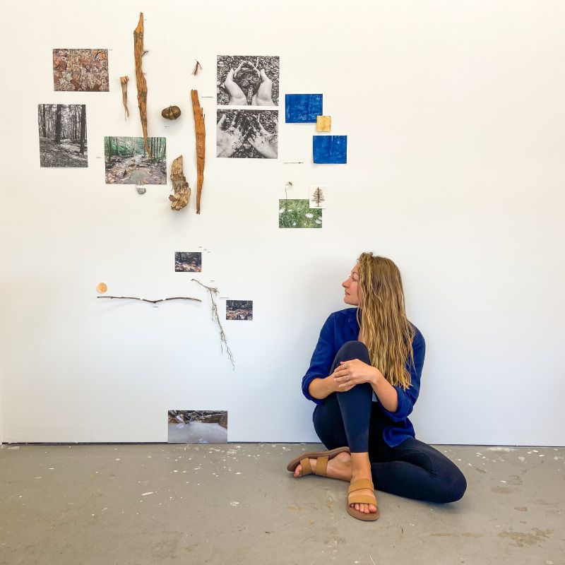 Marley Massey Parsons sits against a wall displaying her artwork