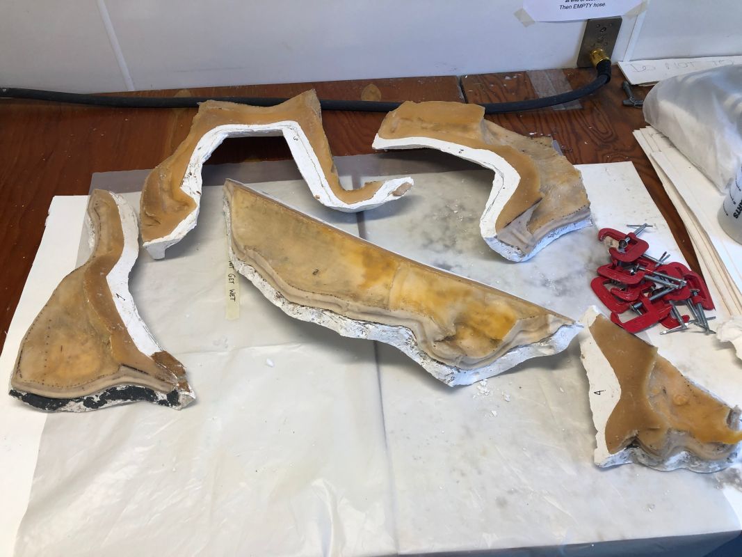 Sections of a plaster mold lie disassembled on a table