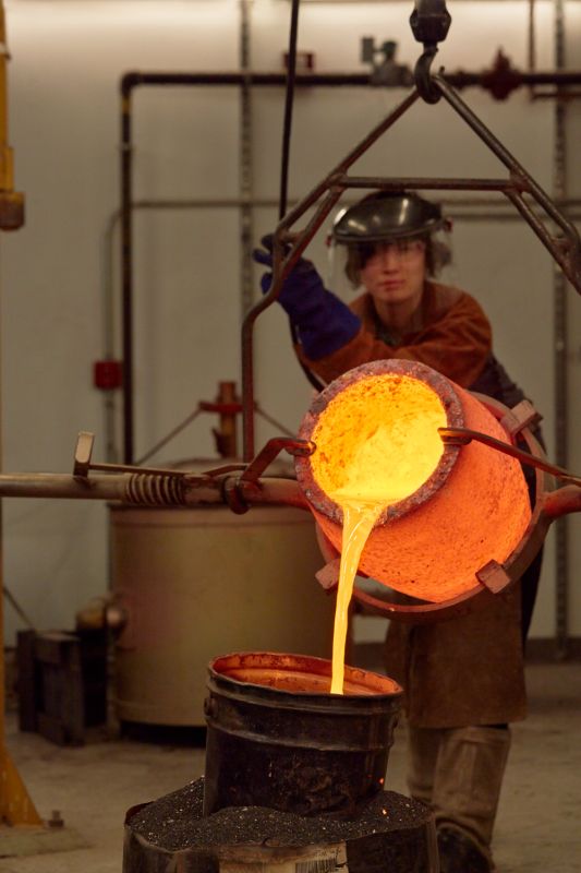 Student pouring molten metal into casting