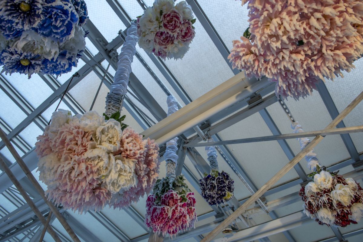 Detail of installed sculpture of hanging wax bouquets from skylight