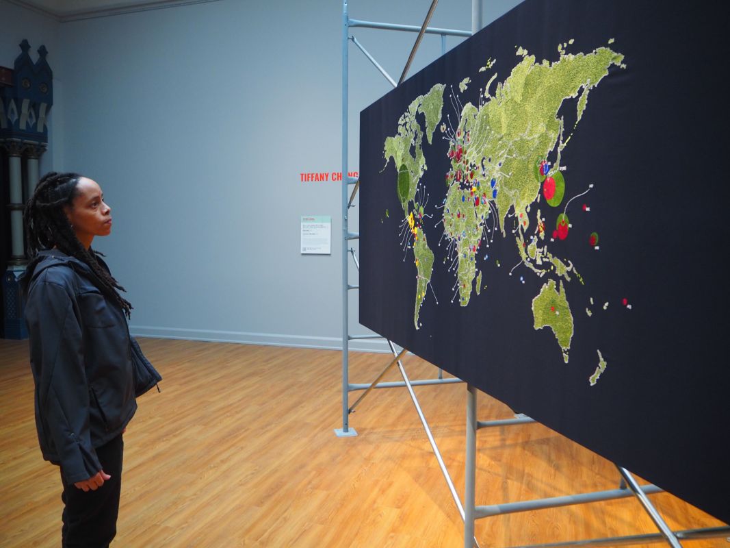 Jeshima looking at large embroidered map in gallery
