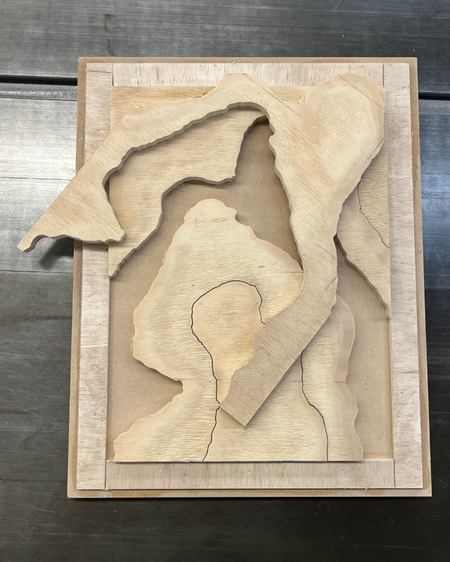 a piece of multi-layered wooden art, likely a topographical map or abstract design. 