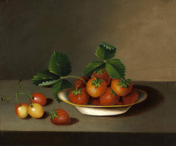 A still life features ripe strawberries and cherries on a wooden table. The strawberries are on a white plate with green leaves, set against a neutral background.