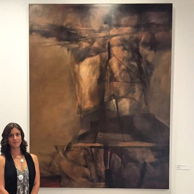 A woman stands next to a massive, abstract figurative oil painting dominated by dark brown tones, expressive gestural lines, and fragmented human forms.