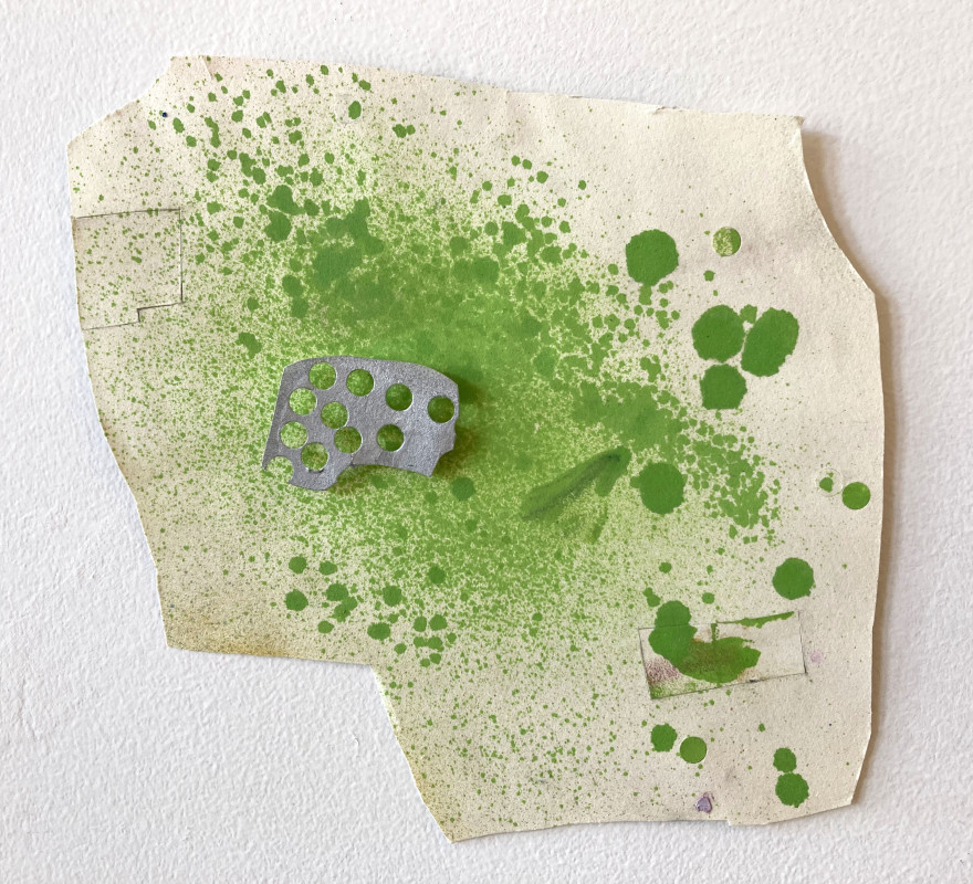 An abstract mixed-media collage on irregular, off-white paper features vibrant green ink splatters, a small perforated metal fragment, and faint pieces of tape against a plain white background.