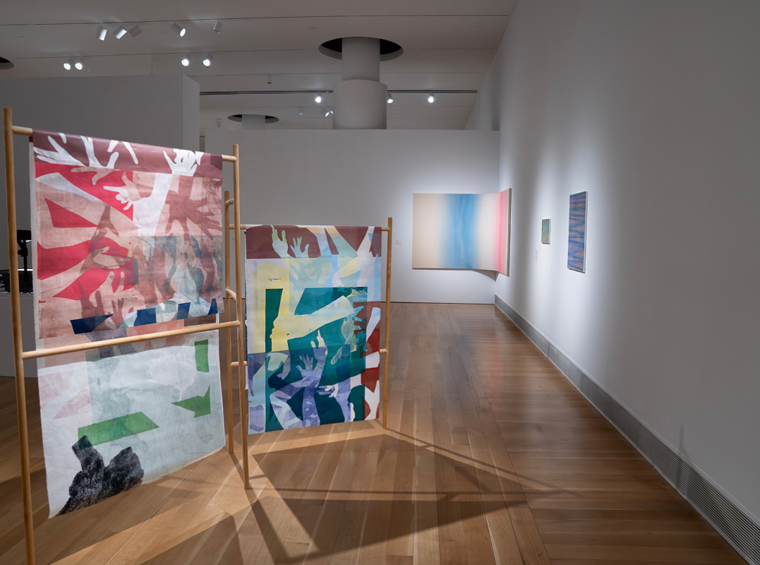 This installation view features printmaking and textile works on wooden display structures, characteristic of contemporary graduate thesis exhibitions showcasing process-based abstraction and mono-prints on paper.