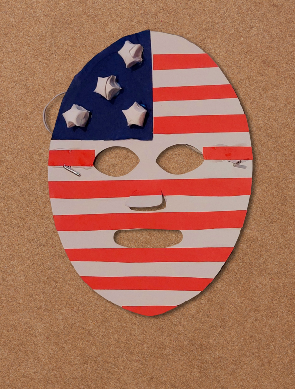 An oval-shaped, handmade patriotic paper mask is decorated with red and white horizontal stripes, featuring five small 3D origami paper stars on a painted blue section in the upper left corner.