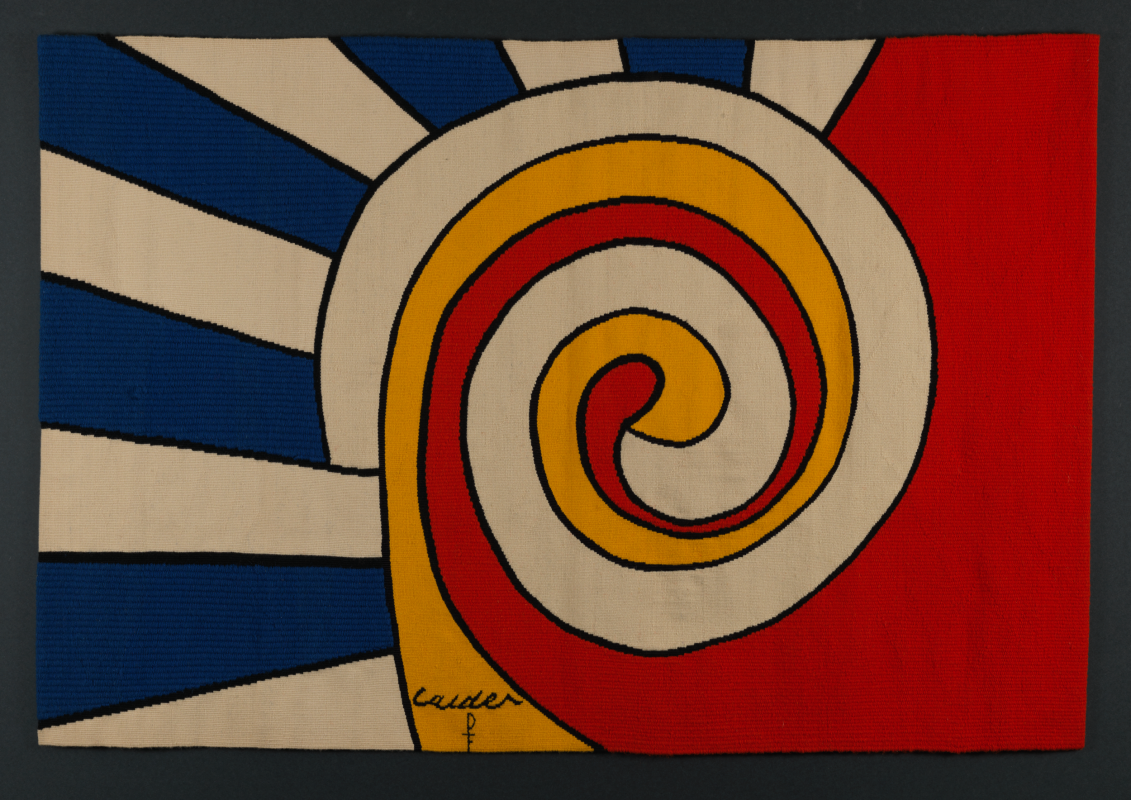 A vibrant tapestry featuring a large central spiral pattern in cream, yellow, and red, contrasted by bold blue-and-white radiating stripes on the left and a solid red block on the right.