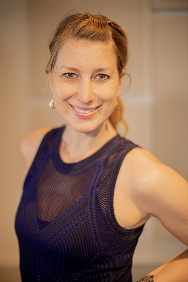 bio photo of Lori McAlister smiling wearing a sleeveless black leotard. 