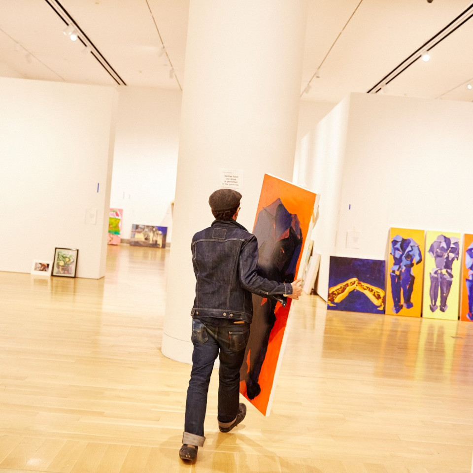 artist carrying artwork into gallery space