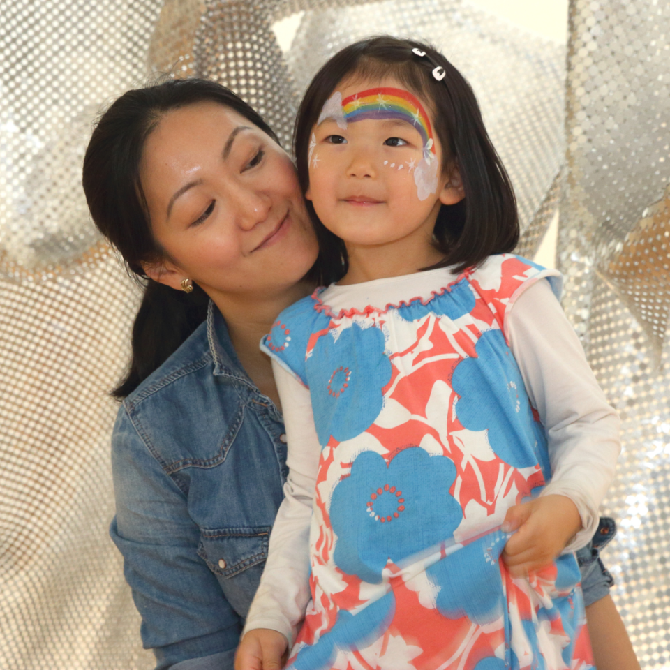 Parent and child, with rainbow face painting, posing.