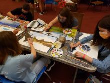 students around table paining landscapes