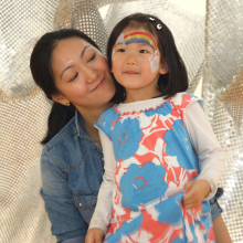 Parent and child, with rainbow face painting, posing.