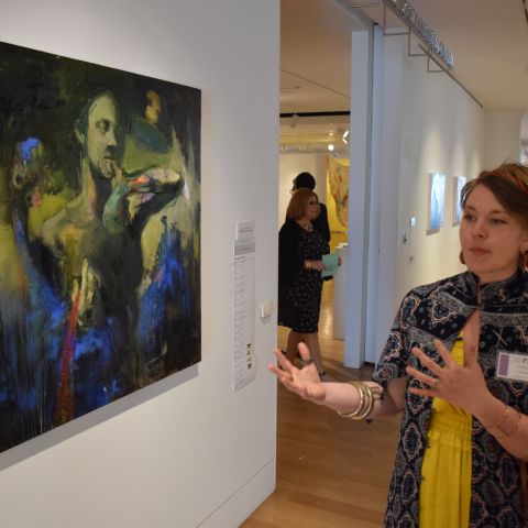 Candace Jensen speaks to visitor in front of painting at ASE Preview Party