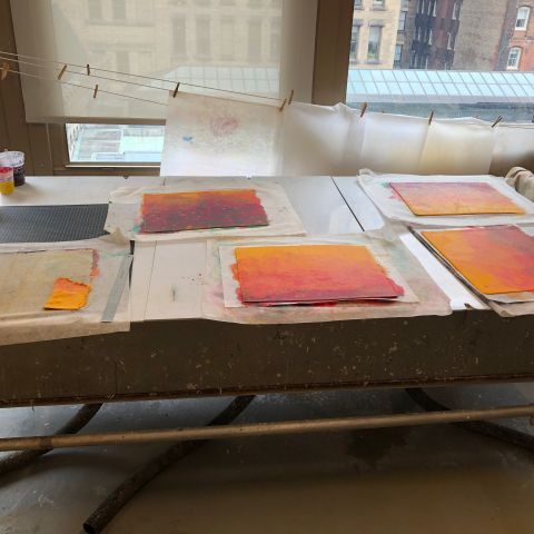 Custom sheets of paper in yellow, orange, and red dry on a large table