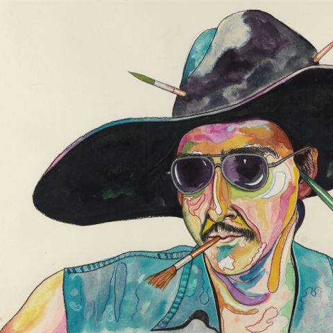 Man wearing hat and sunglasses with paintbrush in his mouth