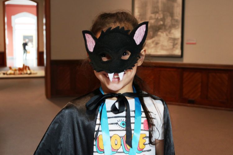 child wearing a bat mask