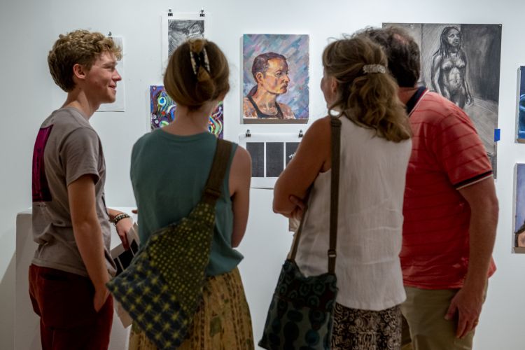 4 students looking at artwork in an exhibition. 