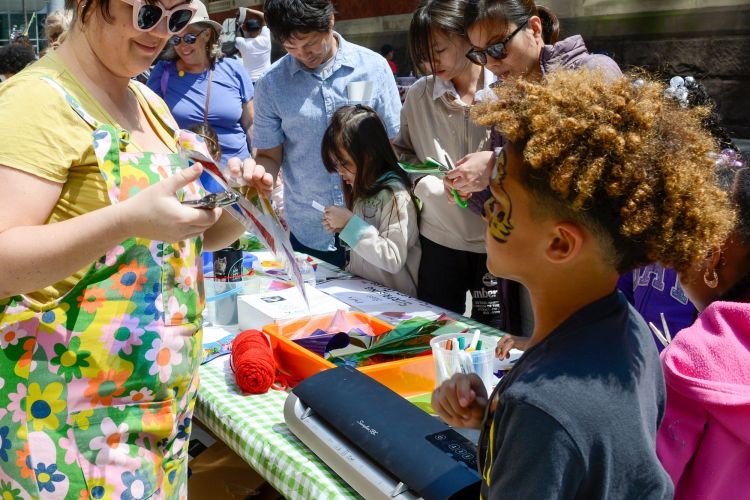 an adult helping a kid at a arts and crafts table during the Spring Festival