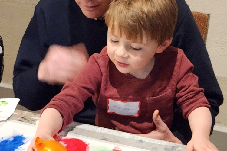 A man and a young boy engaging in a common children's art activity: balloon painting. 