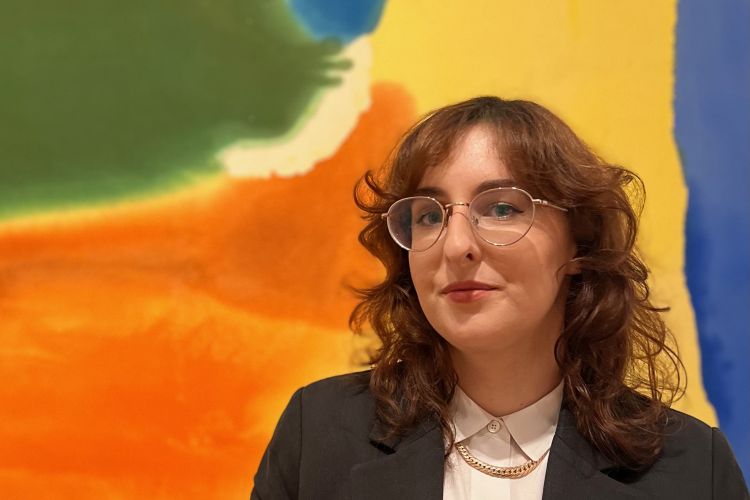 Headshot of art historian Michelle Donnelly smiling in front of an abstract painting.