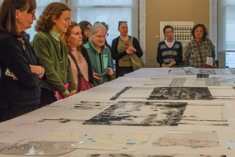 people gathered around a table looking at prints