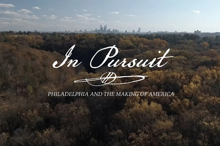 Aerial view of a vast autumn forest with Philadelphia's skyline in the distance. Text overlay reads "In Pursuit: Philadelphia and the Making of America."